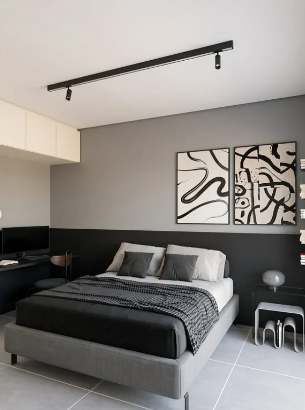 Vista frontal do quarto do AP Entre Tons, com cama cinza, painéis escuros e dois quadros em preto e branco.