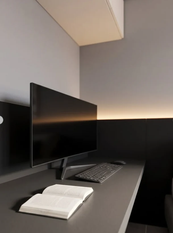 Bancada escura com monitor, livro aberto e iluminação indireta no AP Entre Tons.